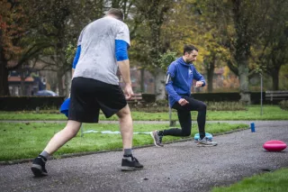 Sportinstructeur Maarten Westerhuis kijkt op zijn stopwatch terwijl hij een meneer aan het trainen is